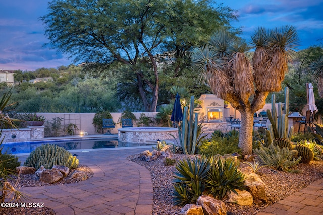 patio terrace at dusk with a swimming pool with hot tub