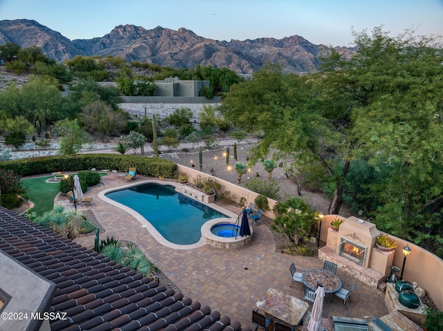 view of pool with a mountain view, a patio area, an outdoor fireplace, and a grill