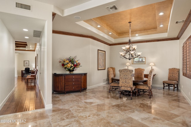 dining room featuring an inviting chandelier, crown molding, a tray ceiling, and light hardwood / wood-style flooring