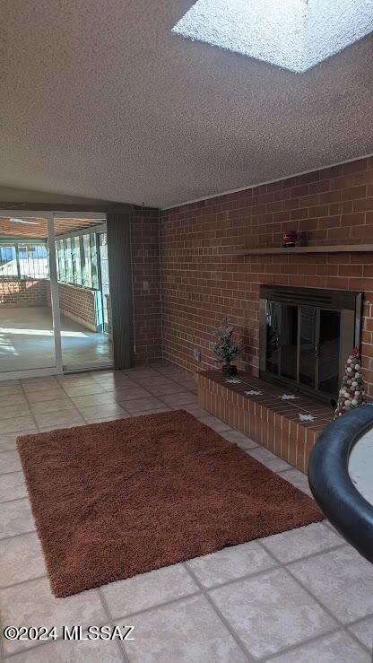 unfurnished living room with a fireplace, brick wall, and a textured ceiling