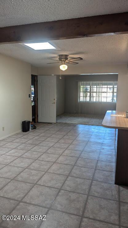 empty room with beamed ceiling, ceiling fan, and a textured ceiling