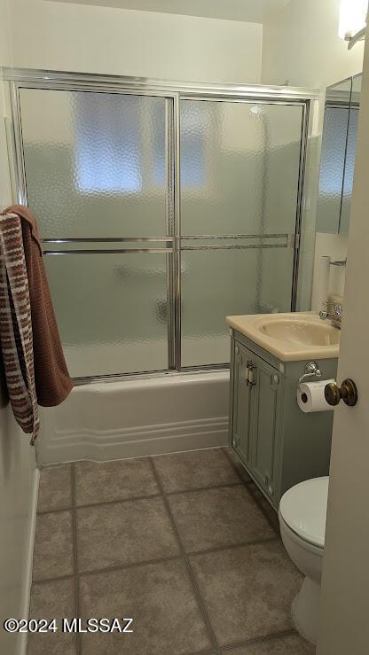 full bathroom featuring combined bath / shower with glass door, tile patterned floors, toilet, and sink