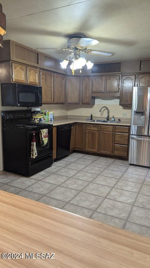 kitchen with sink, light wood-type flooring, dark brown cabinetry, and black appliances