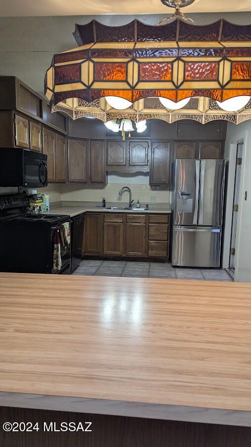 kitchen featuring black appliances, dark brown cabinetry, and sink