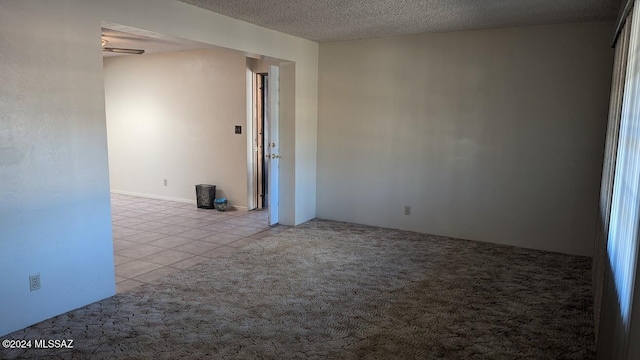 empty room featuring ceiling fan, light colored carpet, and a textured ceiling