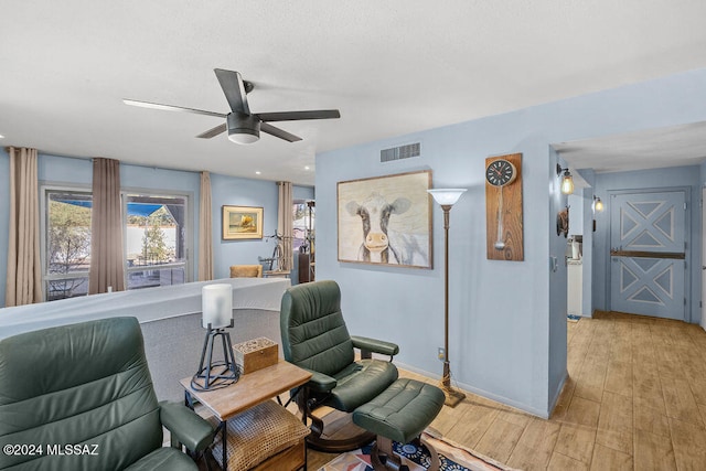 living area with ceiling fan and light hardwood / wood-style flooring