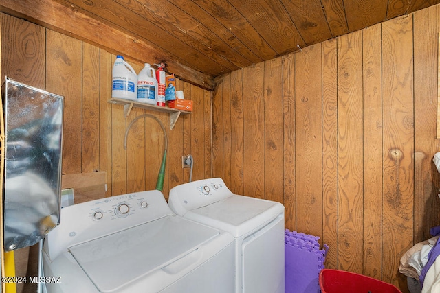 clothes washing area featuring wood walls, washing machine and dryer, and wooden ceiling