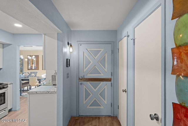 hall featuring light hardwood / wood-style floors and a chandelier