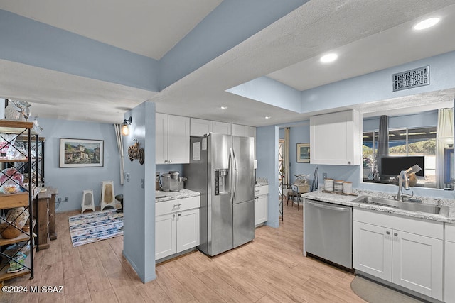 kitchen featuring white cabinets, light wood-type flooring, sink, and appliances with stainless steel finishes