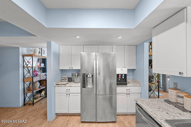 kitchen featuring stainless steel appliances, white cabinetry, light hardwood / wood-style floors, and light stone counters