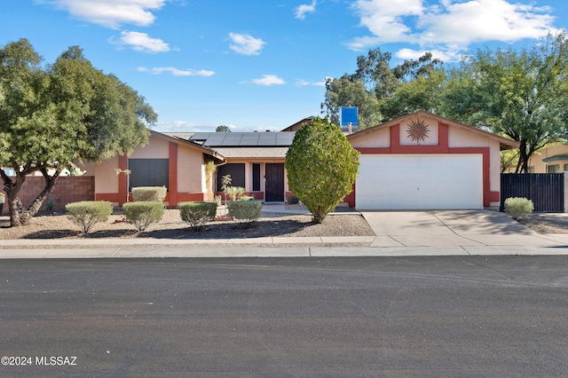 ranch-style home featuring a garage and solar panels