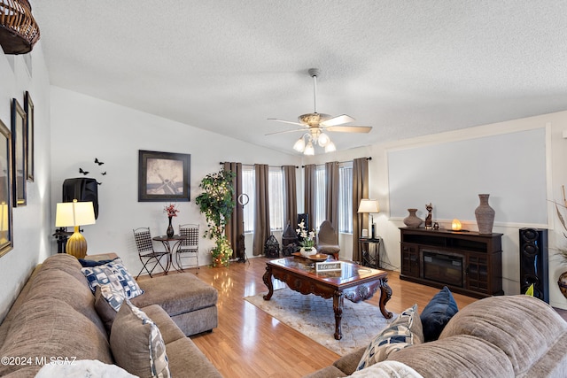 living room featuring a textured ceiling, light hardwood / wood-style flooring, ceiling fan, and lofted ceiling