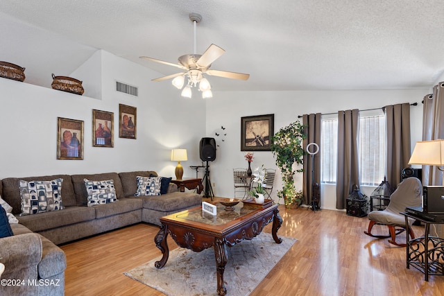 living room with hardwood / wood-style flooring, ceiling fan, lofted ceiling, and a textured ceiling