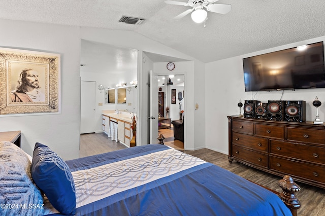 bedroom featuring a textured ceiling, vaulted ceiling, ceiling fan, hardwood / wood-style floors, and connected bathroom