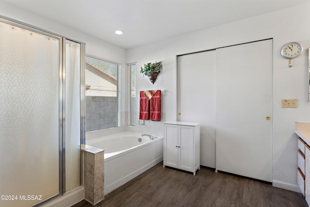 bathroom with vanity, wood-type flooring, and plus walk in shower