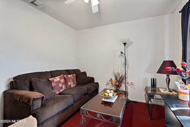 living room with ceiling fan, a textured ceiling, and dark colored carpet