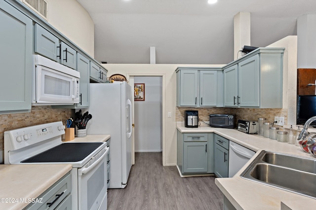 kitchen featuring sink, tasteful backsplash, lofted ceiling, white appliances, and light wood-type flooring