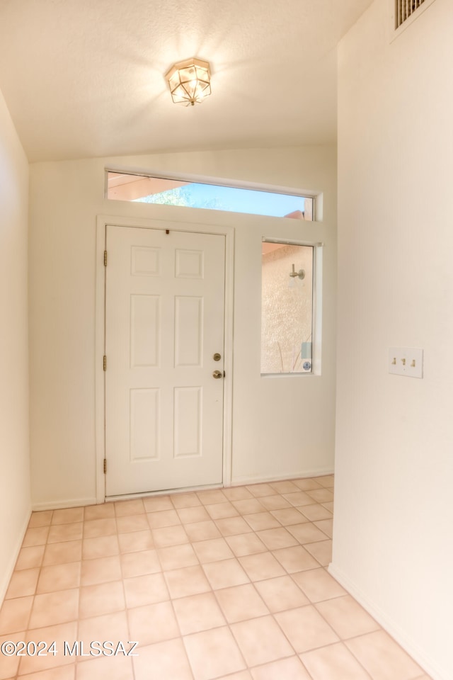 foyer featuring light tile patterned floors and lofted ceiling