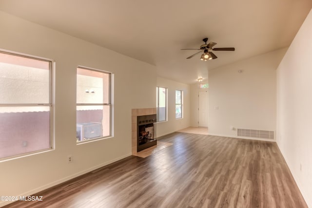 unfurnished living room with hardwood / wood-style floors, ceiling fan, and a tiled fireplace