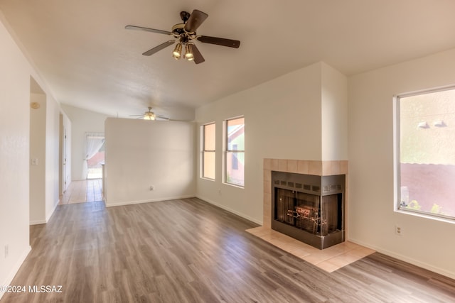 unfurnished living room with a tiled fireplace, plenty of natural light, and light hardwood / wood-style flooring