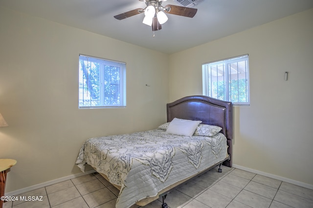 bedroom with ceiling fan, light tile patterned floors, and multiple windows