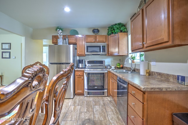 kitchen with sink, stainless steel appliances, and light hardwood / wood-style flooring