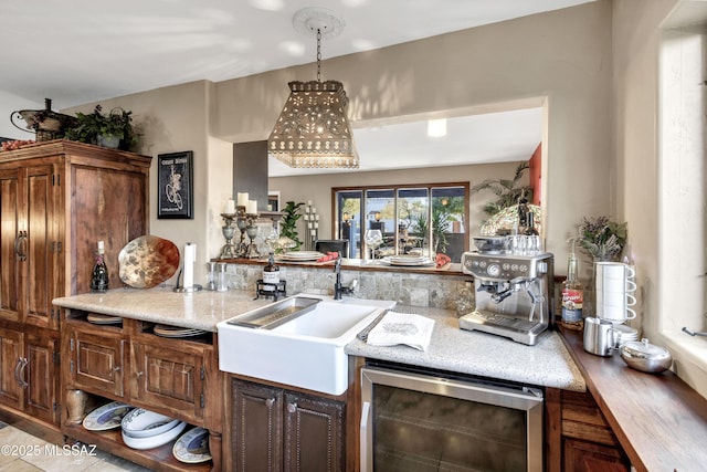 kitchen with dark brown cabinets, decorative light fixtures, beverage cooler, and sink