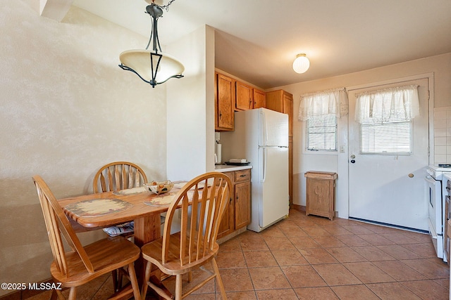 kitchen with white appliances, hanging light fixtures, and light tile patterned floors