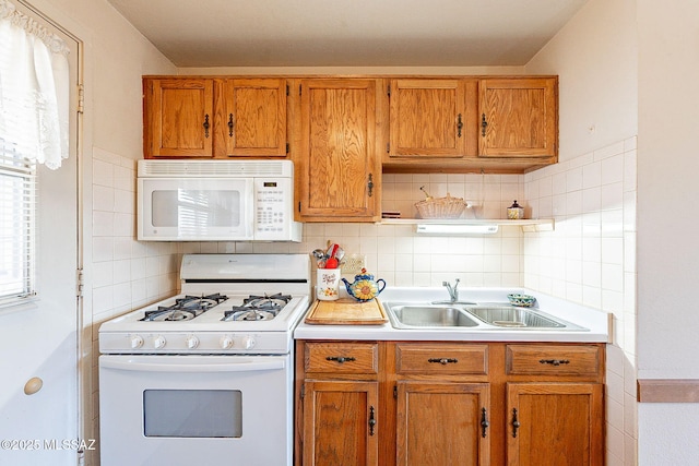 kitchen featuring white appliances, backsplash, and sink