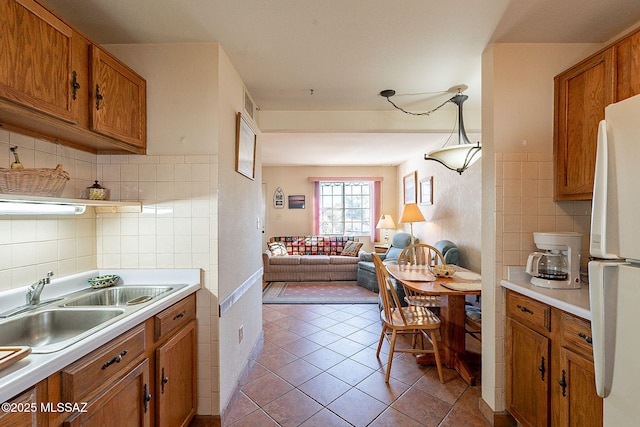 kitchen featuring pendant lighting, white fridge, light tile patterned floors, and sink