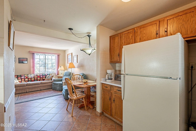 kitchen featuring backsplash, white fridge, hanging light fixtures, and light tile patterned floors