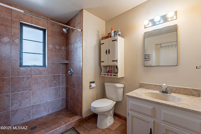 bathroom featuring tile patterned flooring, vanity, toilet, and tiled shower