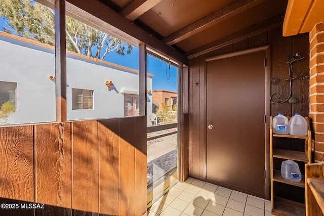 doorway to outside featuring vaulted ceiling with beams and light tile patterned floors