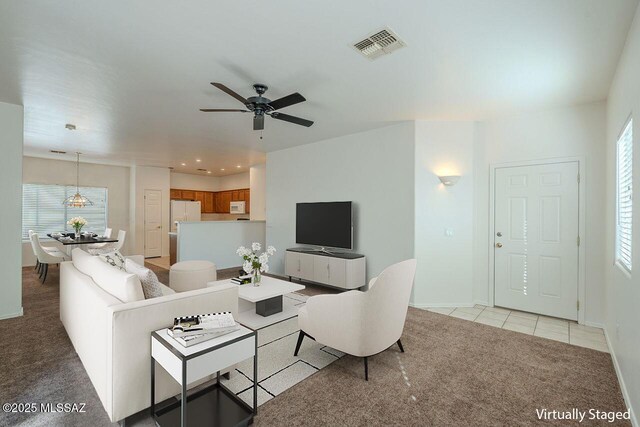 kitchen with ceiling fan with notable chandelier, white appliances, light colored carpet, and hanging light fixtures