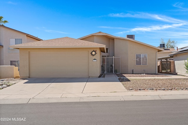 single story home featuring cooling unit and a garage