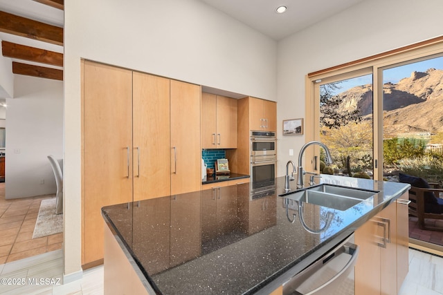 kitchen with appliances with stainless steel finishes, a spacious island, dark stone countertops, and a sink