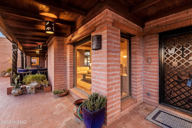 doorway to property featuring brick siding and a porch