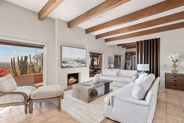 living room featuring beamed ceiling, a lit fireplace, and light tile patterned floors