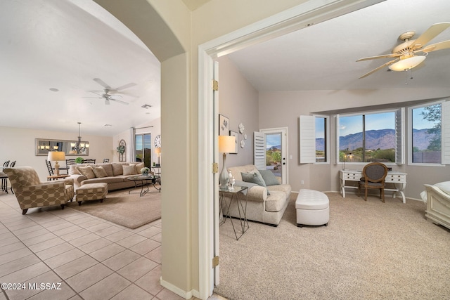 living room featuring a mountain view, light carpet, lofted ceiling, and ceiling fan with notable chandelier