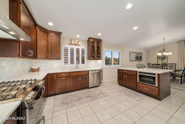 kitchen featuring decorative light fixtures, sink, an inviting chandelier, stainless steel appliances, and wall chimney exhaust hood