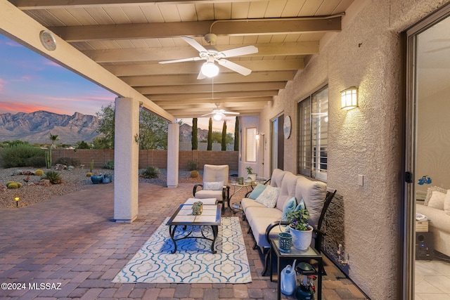 patio terrace at dusk featuring an outdoor hangout area, ceiling fan, and a mountain view