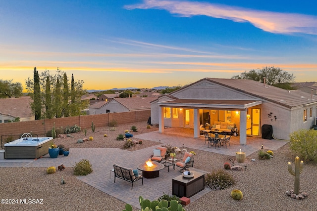 pool at dusk featuring an outdoor fire pit, a hot tub, and a patio area