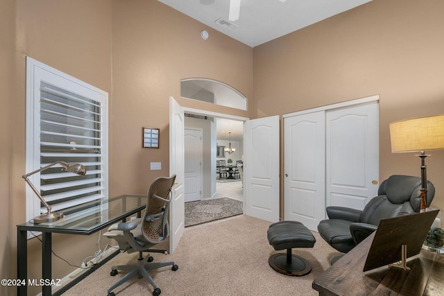 office featuring light carpet, a high ceiling, and a notable chandelier