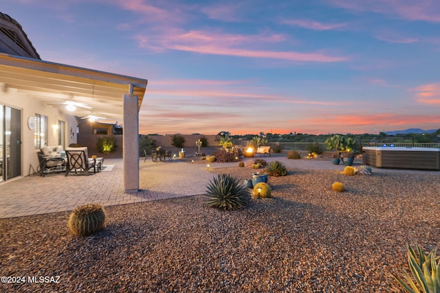 yard at dusk featuring a hot tub and a patio