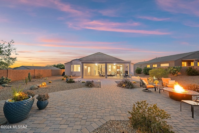 back house at dusk featuring an outdoor fire pit and a patio area