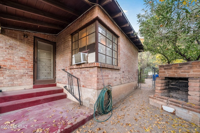 view of home's exterior with cooling unit and an outdoor brick fireplace