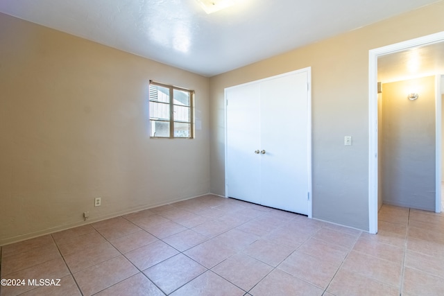 unfurnished bedroom with light tile patterned floors and a closet