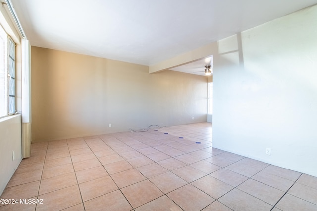 unfurnished room featuring beamed ceiling, ceiling fan, and light tile patterned flooring