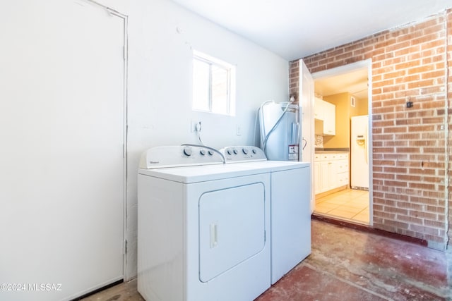 washroom featuring washer and clothes dryer and brick wall