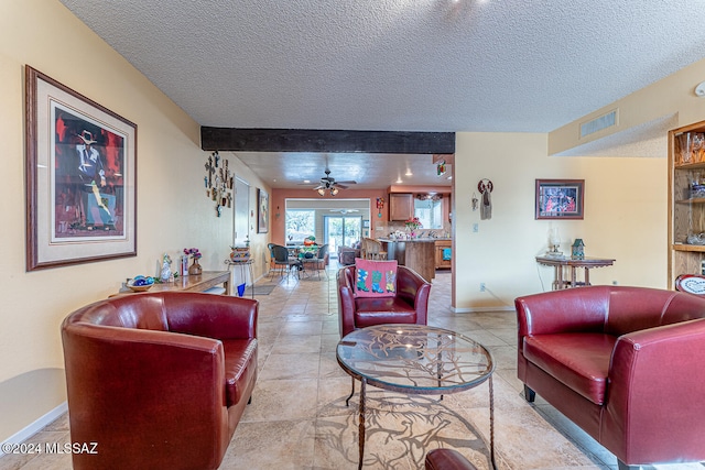 living room with beamed ceiling, ceiling fan, light tile patterned flooring, and a textured ceiling